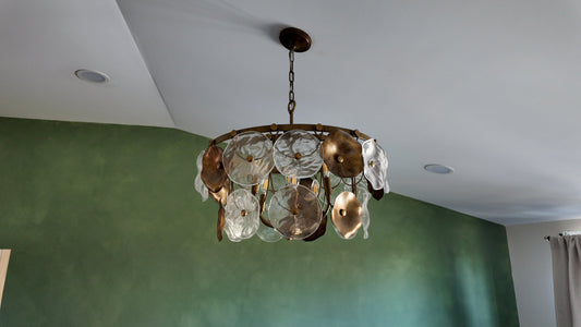 Chandelier hanging from a ceiling with a green wall in the background